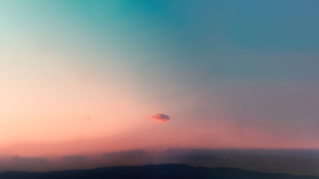 Beautiful pastel sky with a lone cloud during sunset, creating a serene atmosphere.